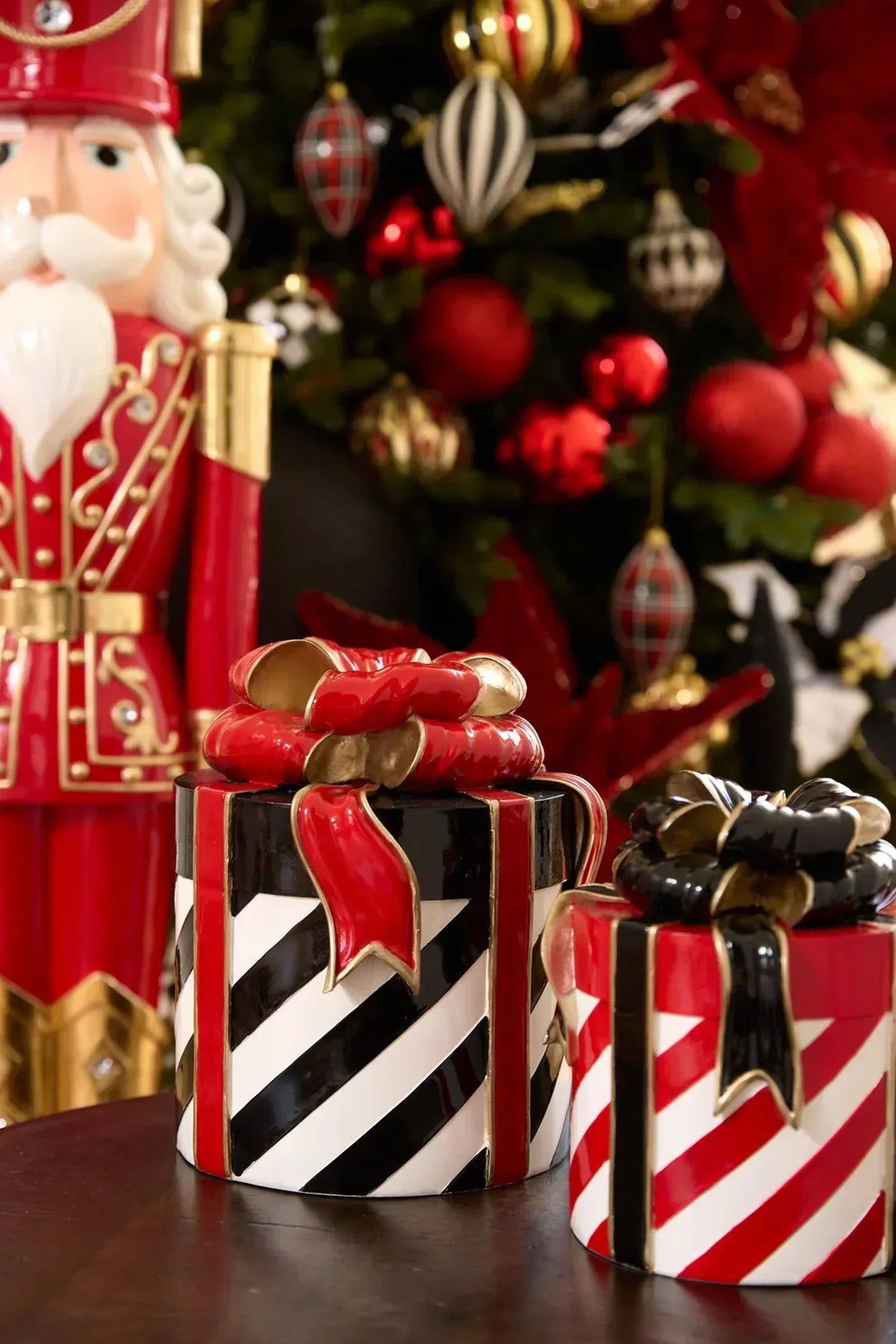 Red and black striped ceramic gift boxes with bows, nutcracker, and Christmas tree decor