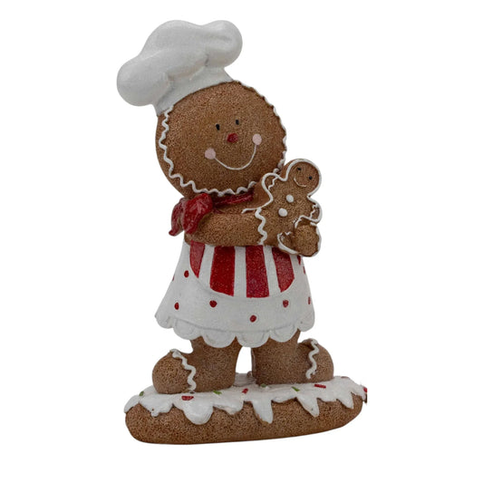 Gingerbread chef figurine holding a mini gingerbread man, festive holiday home decor with red and white apron
