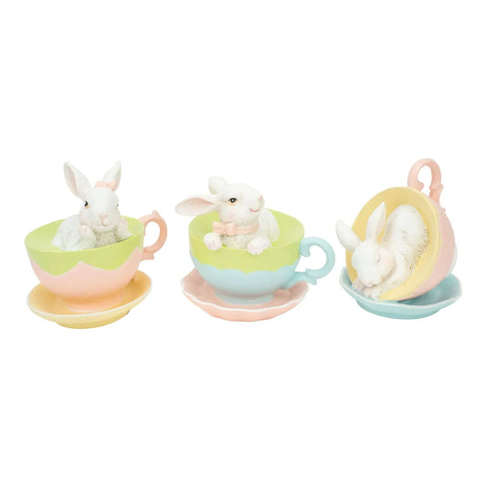 Three white bunny figurines in pastel teacups, cute Easter home decor with saucers