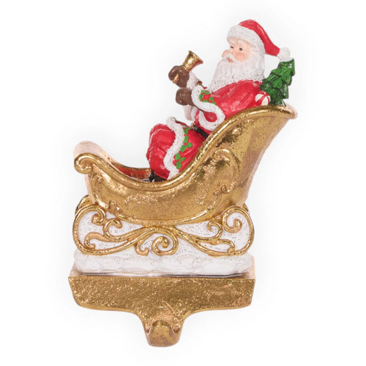 Santa Claus in gold sleigh holding bell, Christmas decoration with festive red suit and green tree