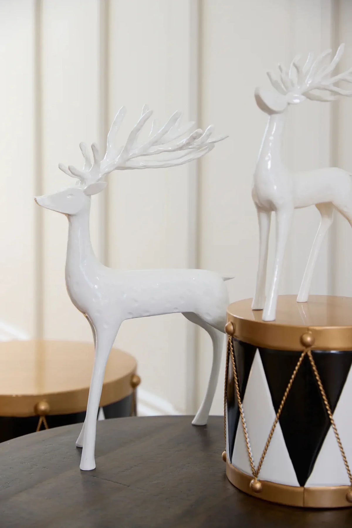White ceramic deer figurines with intricate antlers, styled on a table with geometric decor accents.