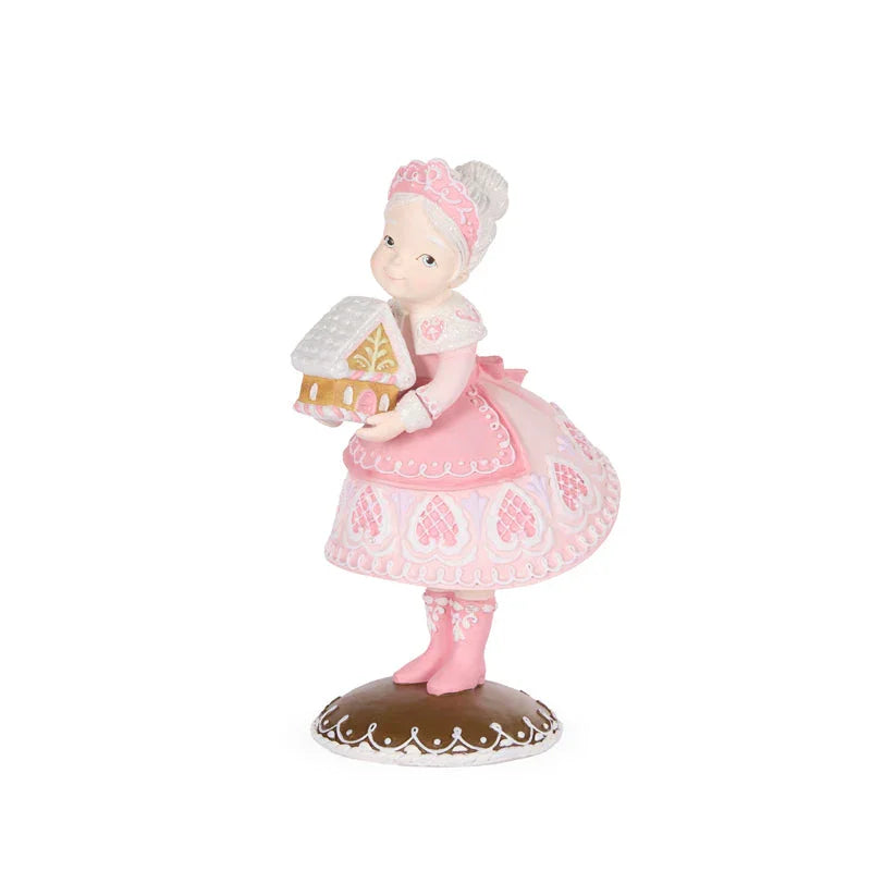 Pink-clad figurine holding gingerbread house, vintage-style home décor accent