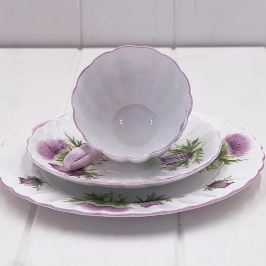Vintage thistle-patterned porcelain teacup, saucer, and plate set with scalloped edges and purple accents