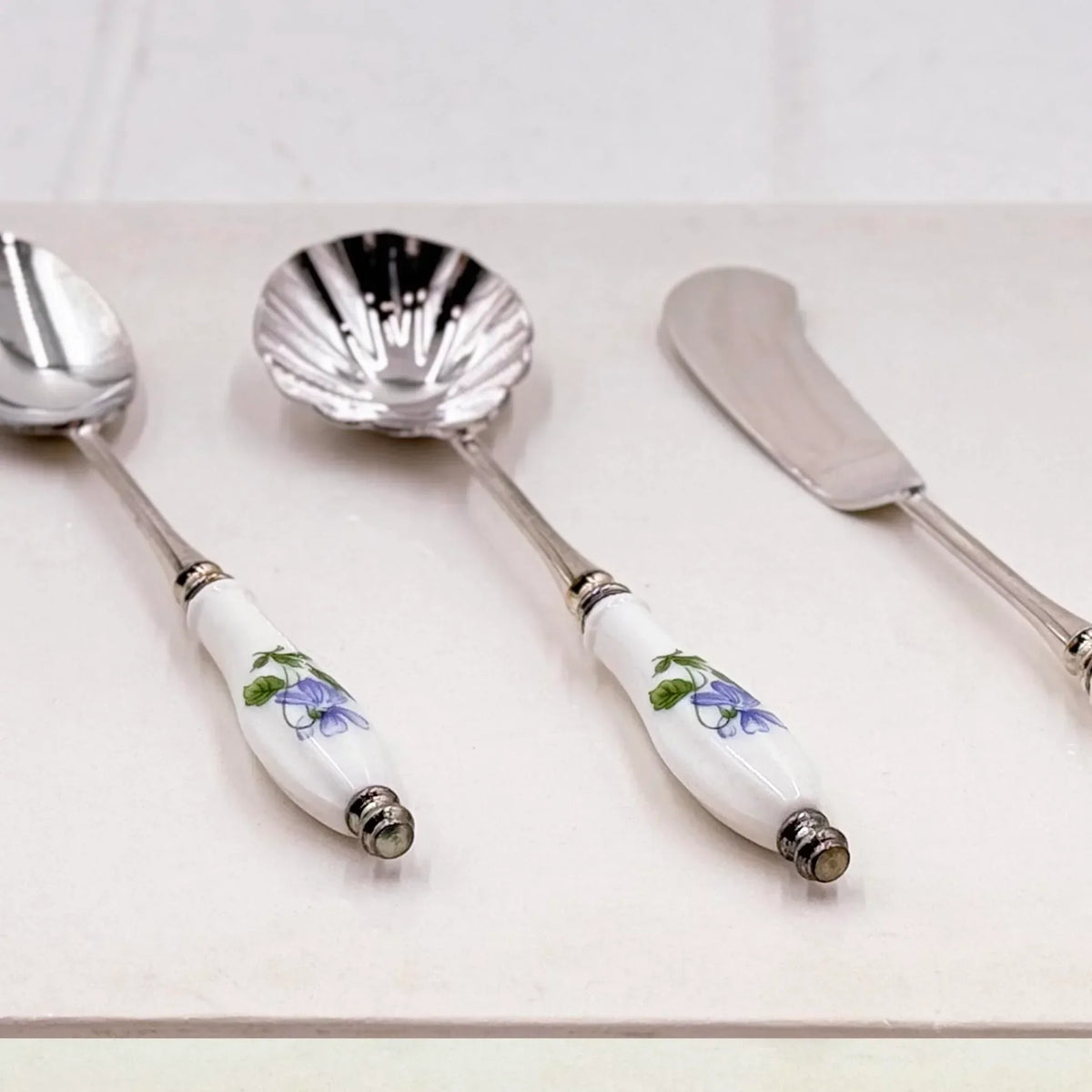 Elegant vintage serving set with floral porcelain handles and silver-toned metal, perfect for home décor