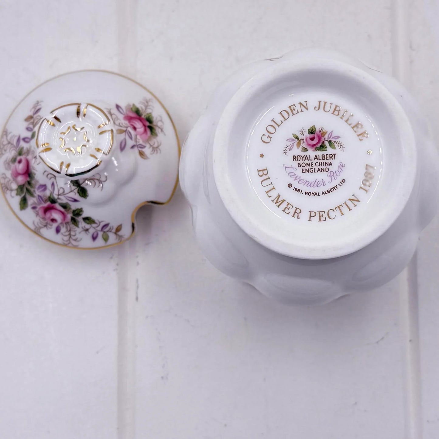A white Royal Albert lavender Rose bone china jam or sugar pot shown from the bottom and lid, featuring gold text reading 'GOLDEN JUBILEE BULMER PECTIN 1997' and pink floral detailing on the lid.
