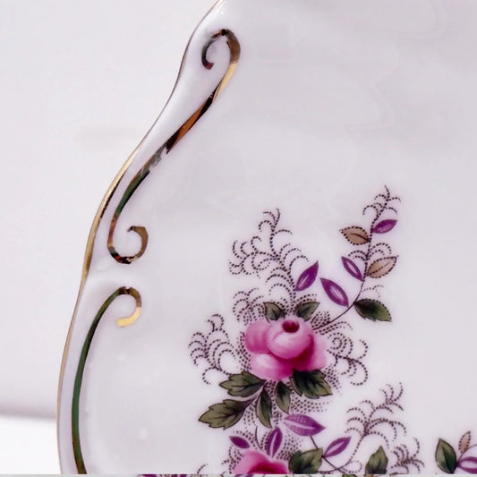 Elegant porcelain plate with pink rose floral design, gold trim, and vintage scrollwork for home décor