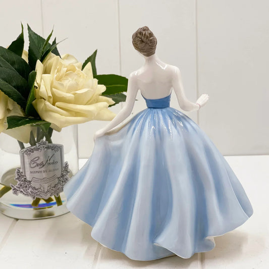 Porcelain figurine of woman in blue gown, elegant home decor with white rose accent