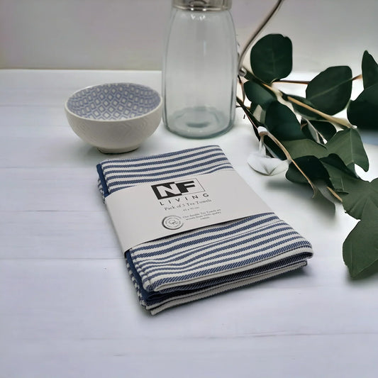 Blue and white striped cotton tea towels, pack of 3, styled with ceramic bowl, glass bottle, and eucalyptus leaves for kitchen décor.