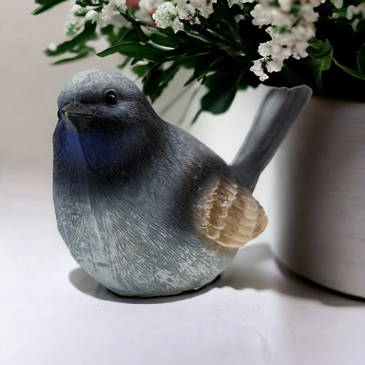 Grey ceramic bird figurine with blue chest, home dƩcor accent near white flowers