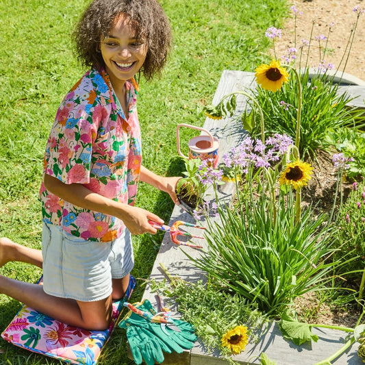 Woman gardening with colorful floral tools, sunflowers, and garden accessories in sunny backyard