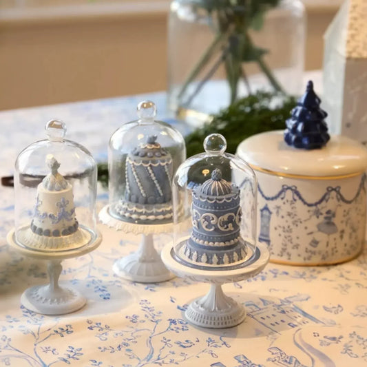 Elegant ceramic cake stands with glass domes, vintage-style home décor on patterned tablecloth