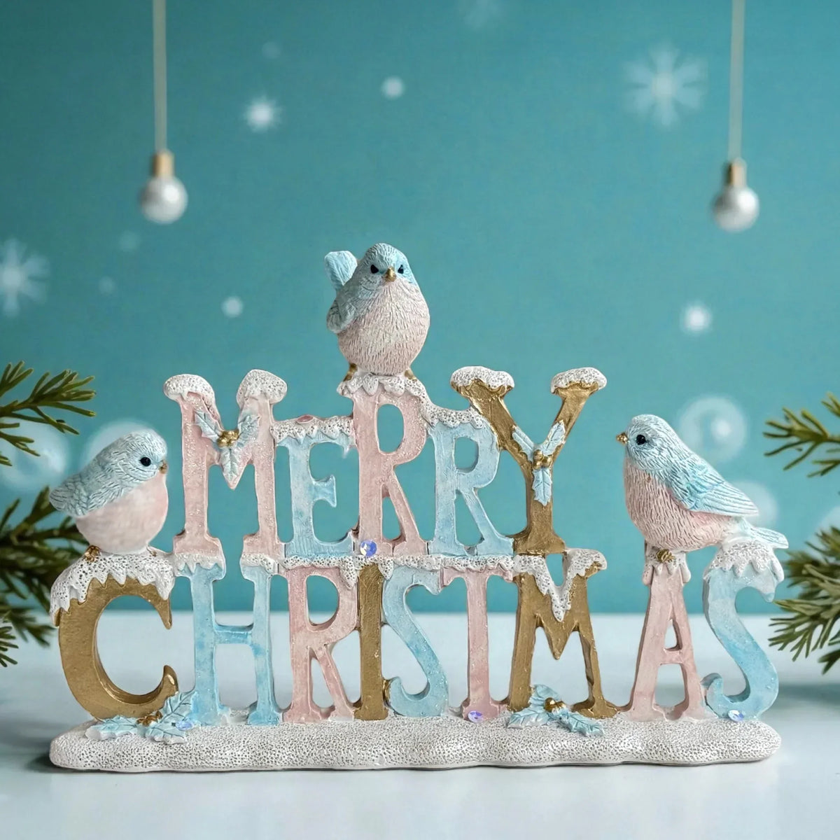 Merry Christmas sign with pastel birds, snow-dusted letters, and festive holiday decor for home tabletop display