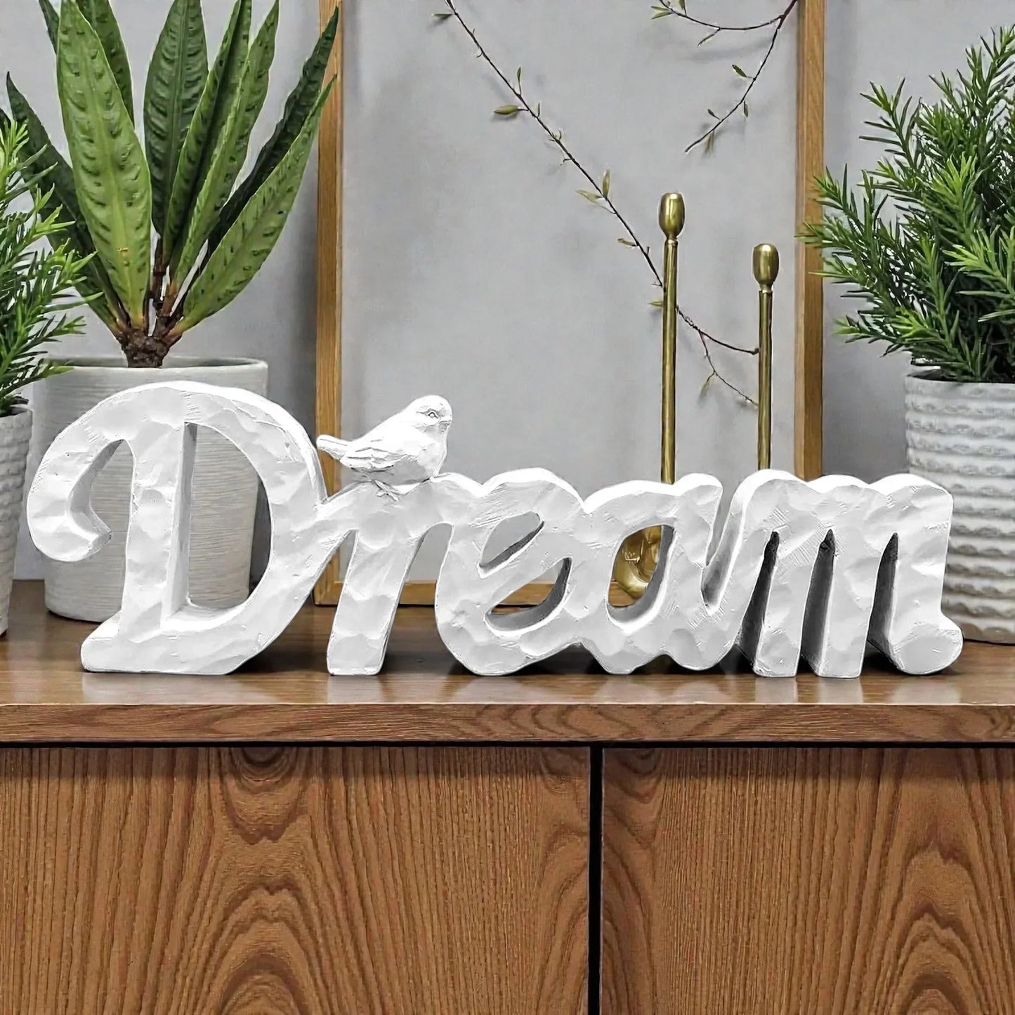 White textured 'Dream' word art with bird, home décor on wooden shelf with plants