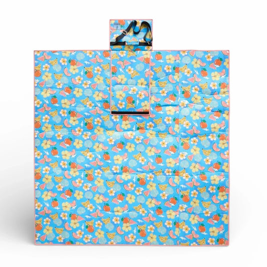 Blue picnic blanket with fruit & flower print, pink trim, and carry strap for outdoor use