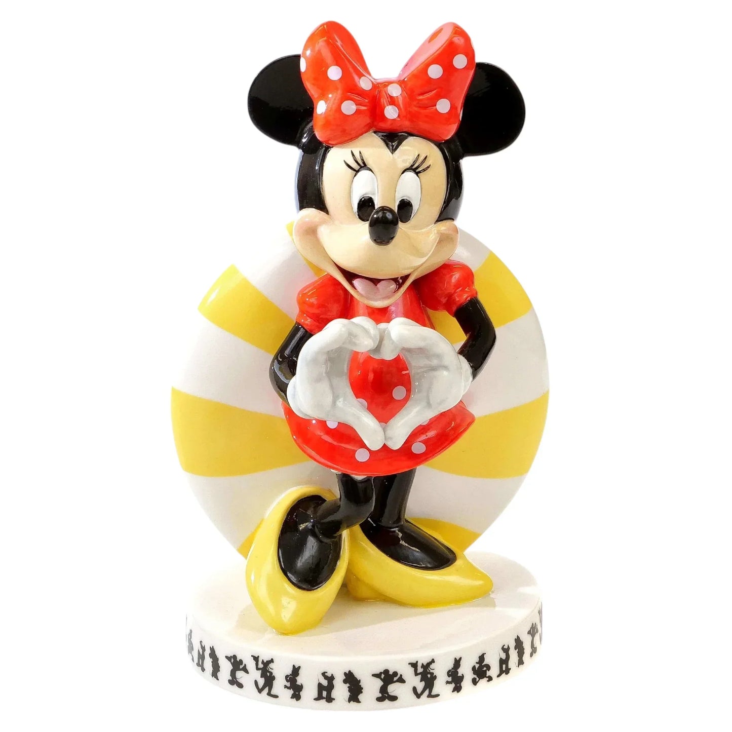 Minnie Mouse figurine making heart shape with hands, red polka dot dress, yellow shoes, striped background