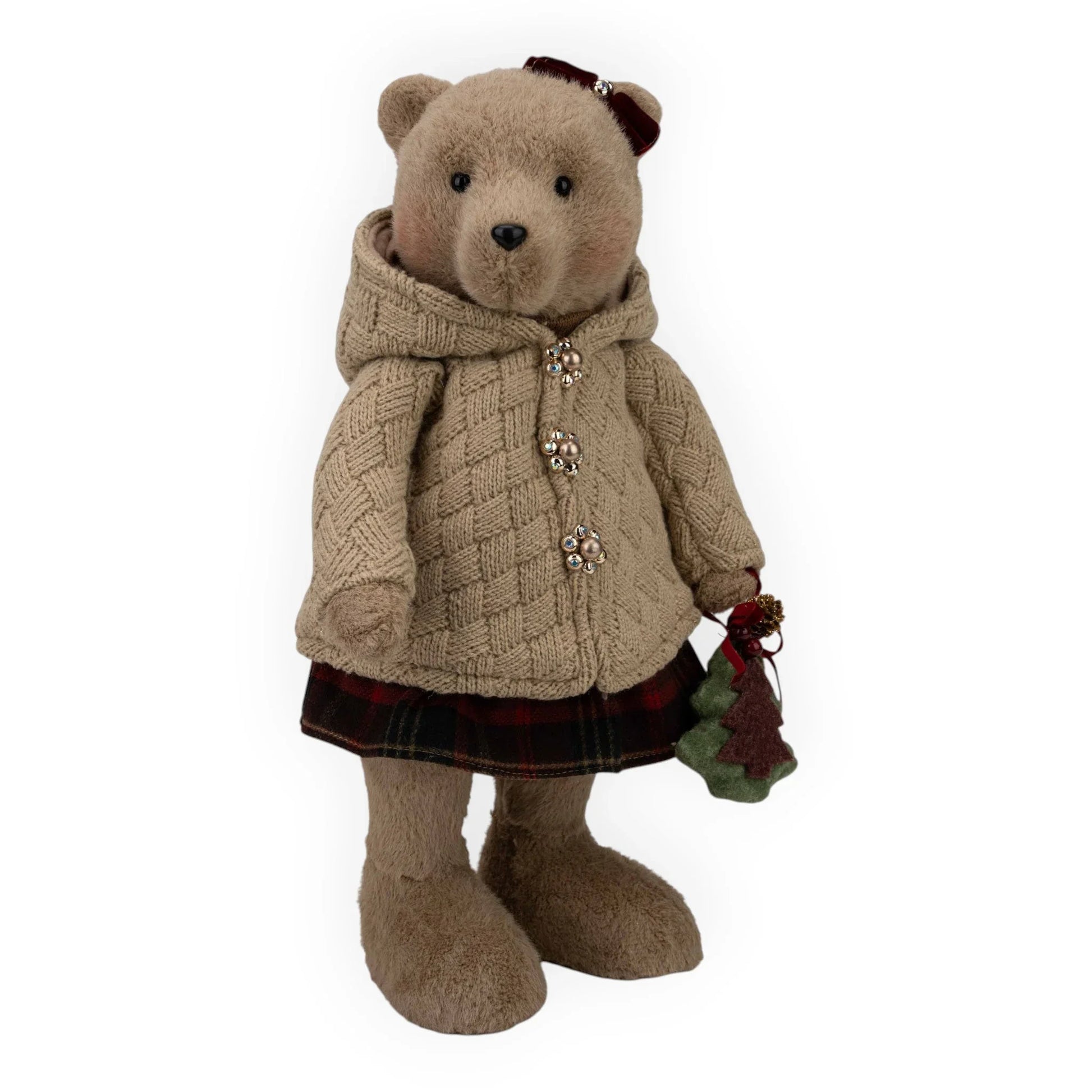 Charming teddy bear in cozy cable knit coat, plaid skirt, holding festive Christmas tree ornament, perfect for holiday home décor.