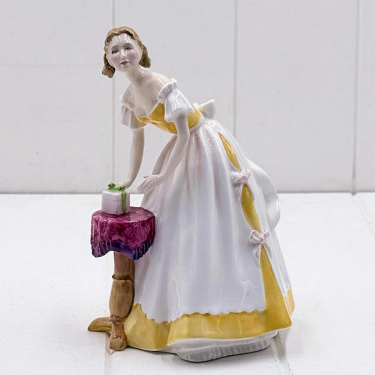 Royal Doulton Happy Birthday figurine HN3095, lady in white and yellow gown leaning over a gift on a side table